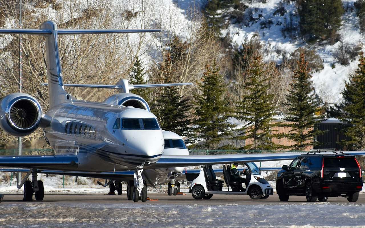 Private jets on a snowy mountain apron, cars waiting beside them