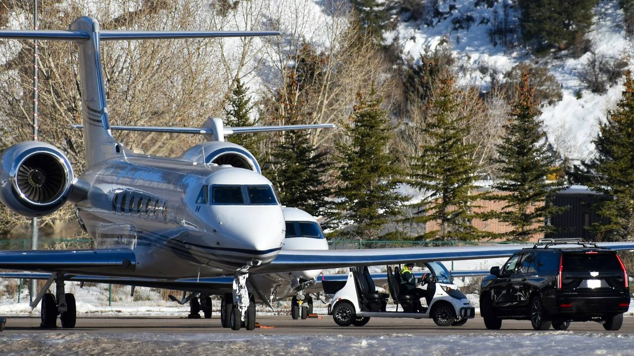 Private jets on a snowy mountain apron, cars waiting beside them