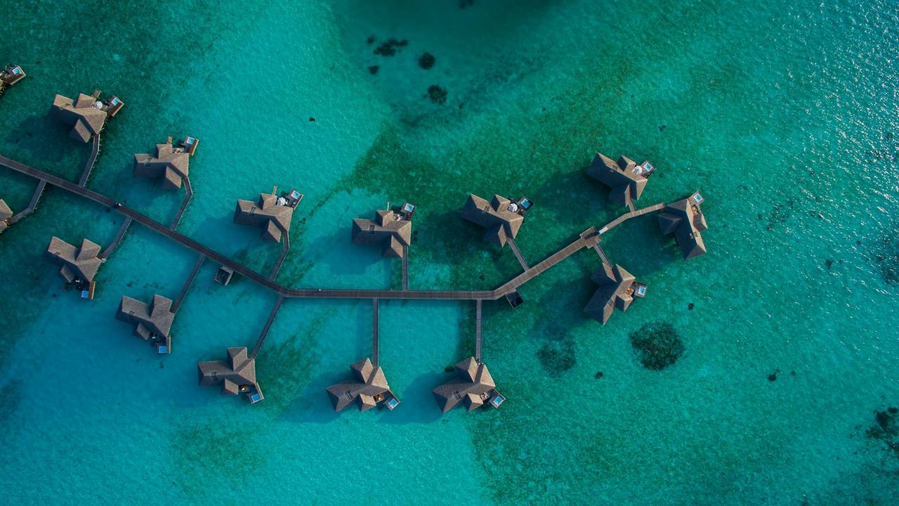 Overwater villas on a turquoise lagoon, seen from above