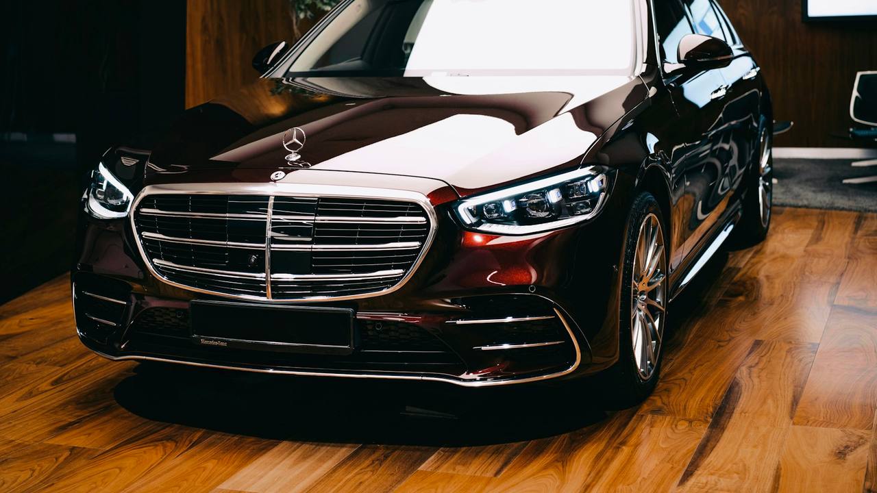 A Mercedes S-Class in deep burgundy, its chrome grille and bonnet star catching the light