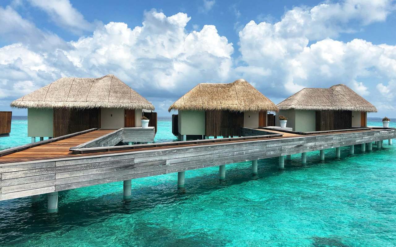 Thatched villas standing over clear turquoise water