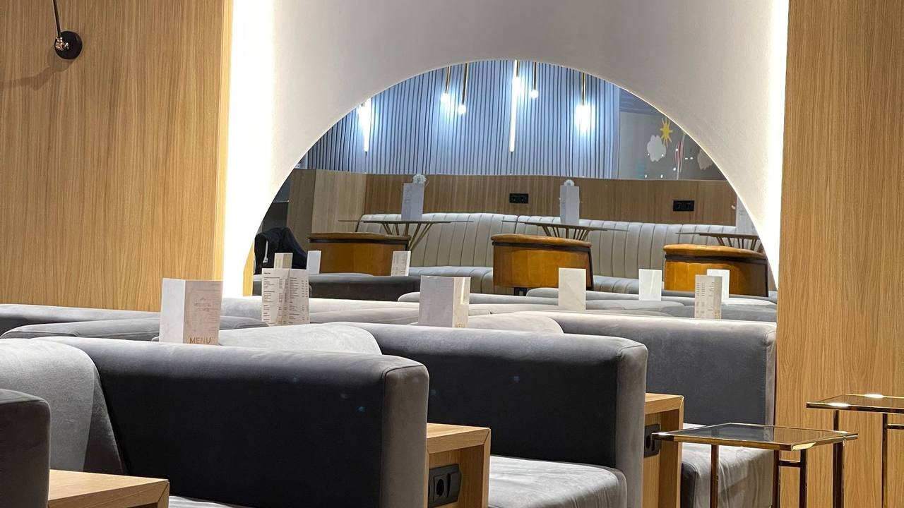 A calm VIP lounge with an arched opening, warm wood and deep armchairs